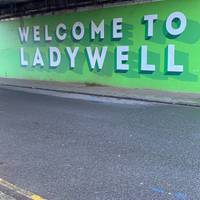 Go under the railway bridge past the ‘Welcome to Ladywell’ mural