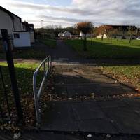 At a fence gap, turn left down the steps. There are some loose slabs & a handrail to left. Go straight ahead over another pavement marker.