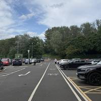 Continue along the designated pedestrian path through the car park.