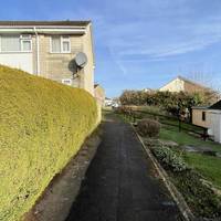 At the end of the road, turn left onto the tarmac footpath with gardens and houses to your right.