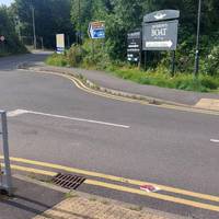 Cross Rifle Road via the tactile paving. Turn left on the other side then follow the pavement round to the right.