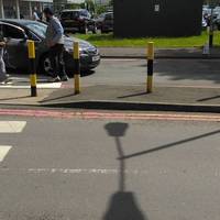 Cross the car park entrance and exit roads using the designated pedestrian crossings.