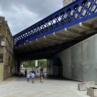Continue walking underneath the blue railway bridge.
