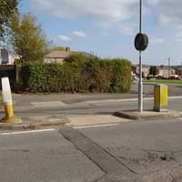 Carefully cross the road using the pedestrian refuge.