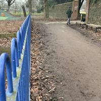 Follow the stone wall (on your right) down to the gap, adjacent to the playground.