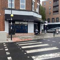 At the junction, use the zebra crossing towards the restaurant. Turn right to follow the pavement around the side of the restaurant.