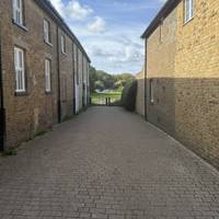 Take the left path as it forks, it’s signposted to the river and takes us between these old houses to an open field.