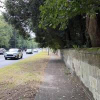Continue along the pavement next to the sandstone wall.