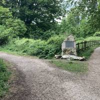 Head along the path until you see this commemorative stone. Notice how quickly the road noise begins to drop away. Take the left-hand fork.