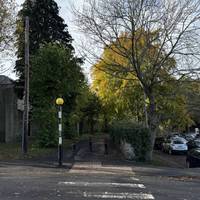 Cross Chisholm Place road at the zebra crossing.