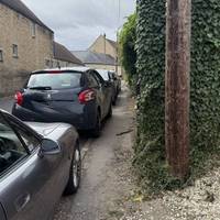 Continue along The Street, cross the road and walk along the narrow pavement beside the parked cars.