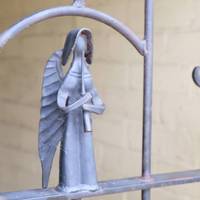 Take time to notice the delicate angel forged from metal on the gate.