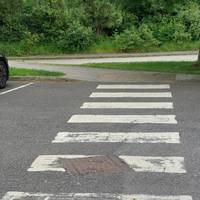 Cross the zebra crossing and follow the path left - drop curbs and level pavements. Slight decline after crossing.