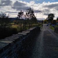 Manse Road is to the right of the car park if the river is in front of you. Cross this stone humpback bridge.