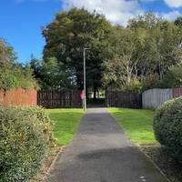 Look out for a tarmac footpath on your left between two houses, and turn onto it.