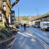 Continue along the road passing blocks of flats and a car park.