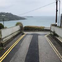 Over this little bridge and turn left down the hill, keep to the pavement along the road until you reach the coastal path. 