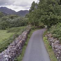 The narrow lane continues,  rising slightly, and with mossy dry-stone walls on either side