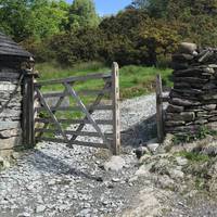 Make your way along the path until you get to the farm houses. Take the gate at the gravel path.