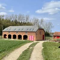 Follow track towards woods passing this barn on your right.