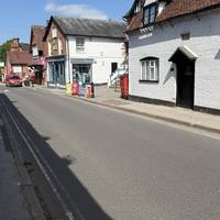 Follow the main road through the village. There are a few shops, a pharmacy and cafes.