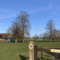 At the security gates, you’ll see a house on the left with a moat. Follow the yellow topped posts to begin walking straight across the park.