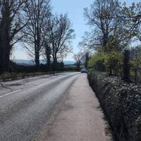 Continuing along the pavement, keeping the low wall and hedgerow on your right taking the views over to your left across the valley