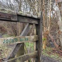 Don't cross over the old stone bridge! The gate marks the entrance to Jock's Burn. Take this path which follows the burn.